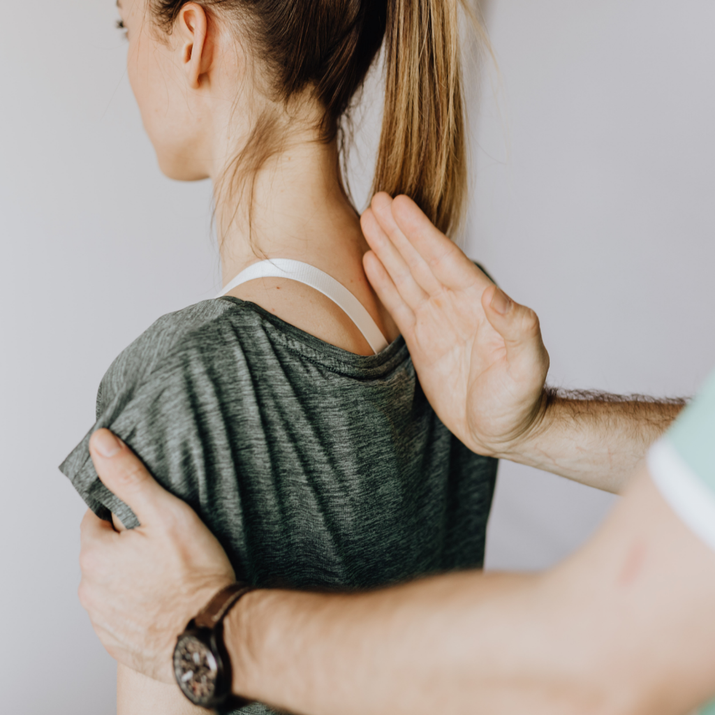 Physiotherapeut führt eine manuelle Behandlung im Schulter- und Nackenbereich einer Patientin durch.