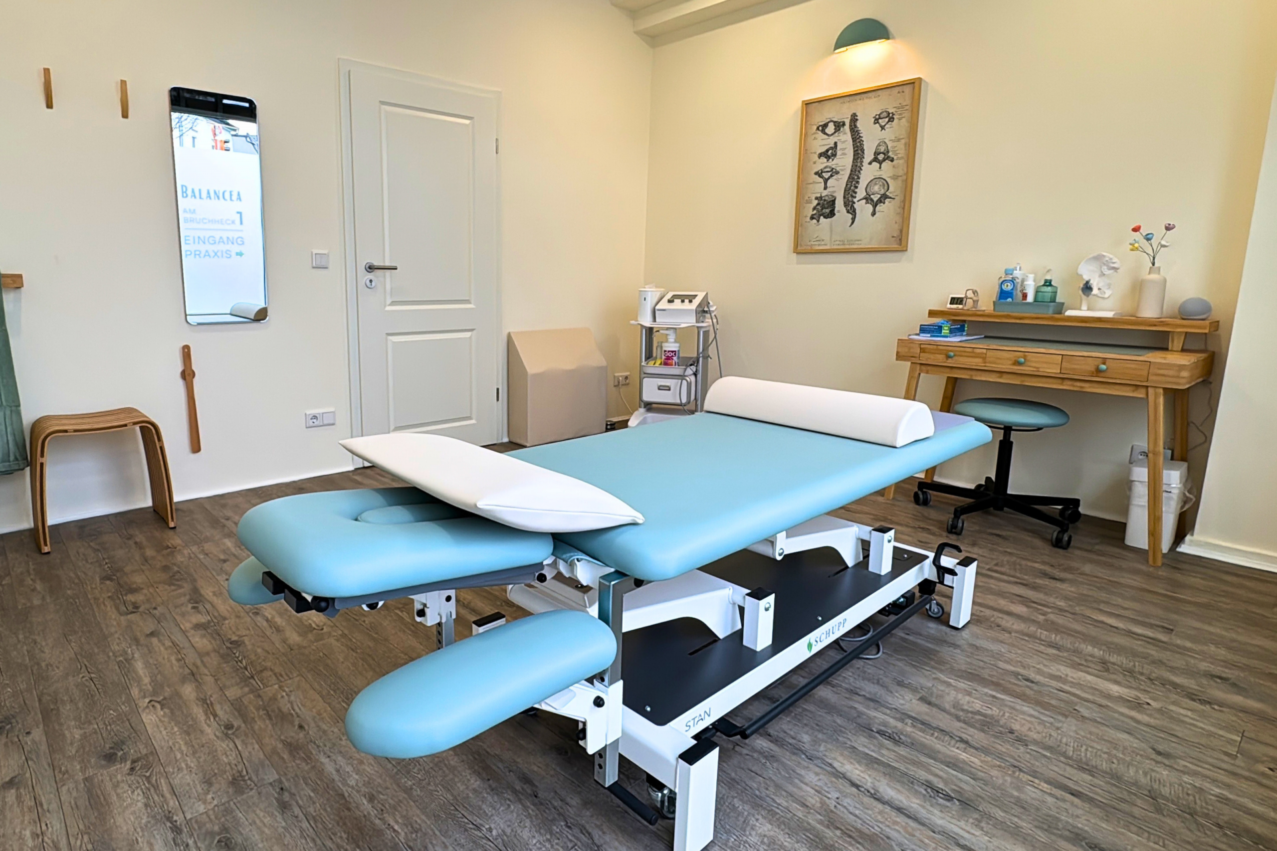 Moderner Behandlungsraum mit höhenverstellbarer Therapieliege, Arbeitsbereich und physiotherapeutischem Equipment. Moderner Behandlungsraum mit höhenverstellbarer Therapieliege, Arbeitsbereich und physiotherapeutischem Equipment.